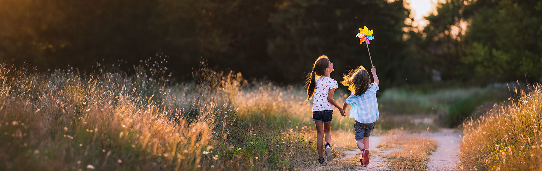 Two children running down a path with a whirly gig
